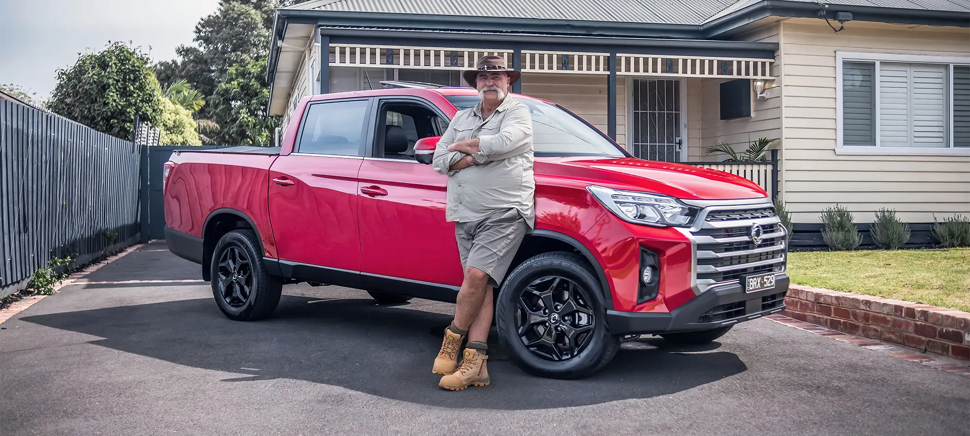 Merv Hughes with a stick sitting in the rear seats of a KGM Rexton SUV